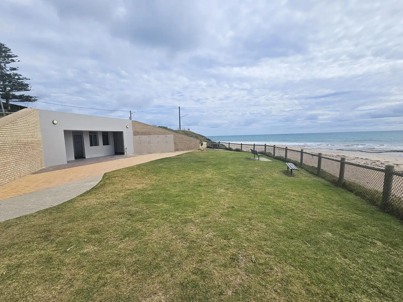 Landscape image showing open grass space with beach in background
